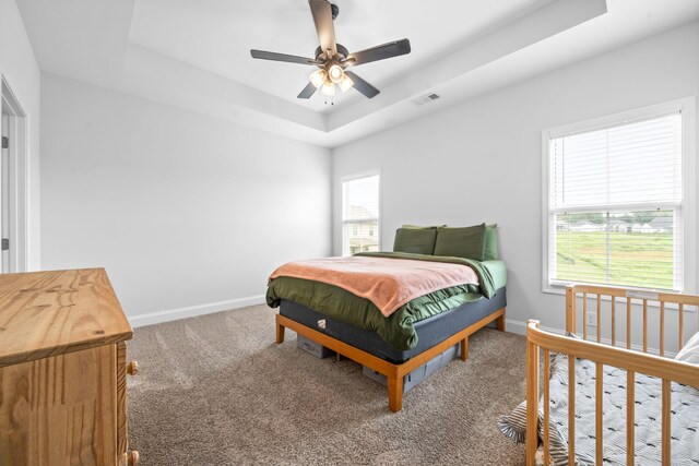 bedroom with ceiling fan, carpet floors, and a raised ceiling