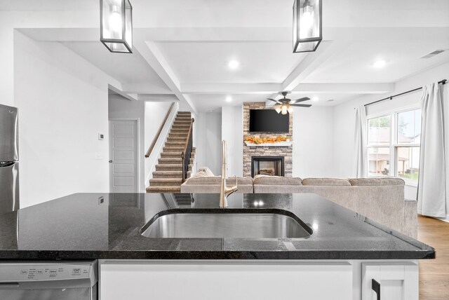 kitchen featuring ceiling fan, a stone fireplace, stainless steel appliances, and decorative light fixtures