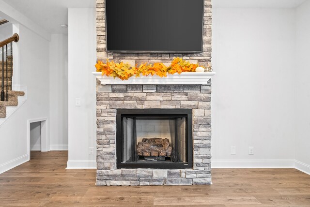 room details featuring a stone fireplace and hardwood / wood-style flooring