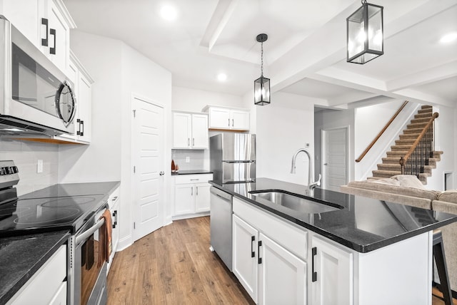 kitchen featuring pendant lighting, sink, tasteful backsplash, a center island with sink, and stainless steel appliances