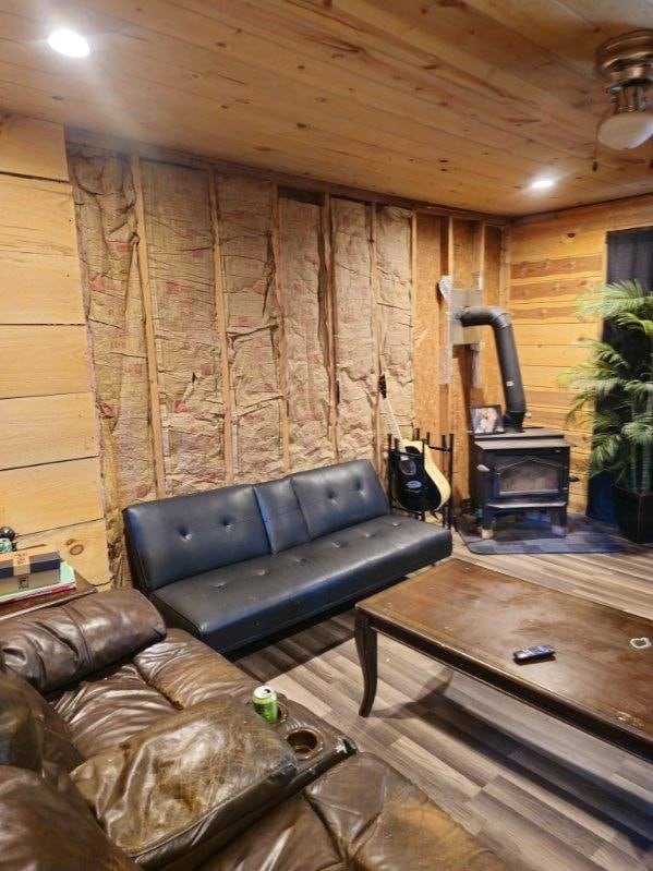 living room with hardwood / wood-style floors, wood walls, a wood stove, and wood ceiling