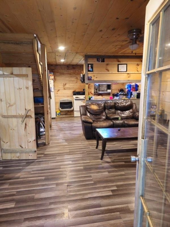 living room featuring heating unit, wood walls, wooden ceiling, and hardwood / wood-style flooring