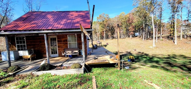 rear view of house featuring a wooden deck and a lawn