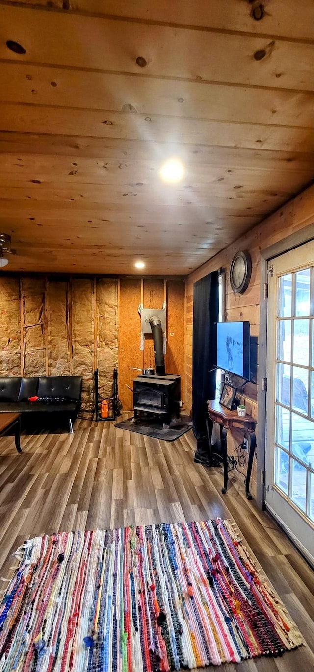 interior space with wood-type flooring, a wood stove, wood walls, and wood ceiling