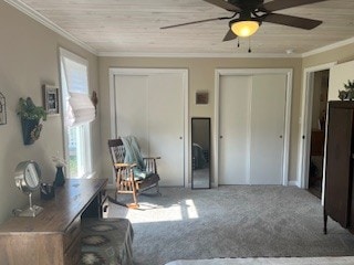 living area with ceiling fan, carpet floors, ornamental molding, and wooden ceiling