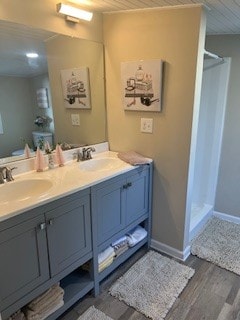 bathroom with wood-type flooring, vanity, and walk in shower