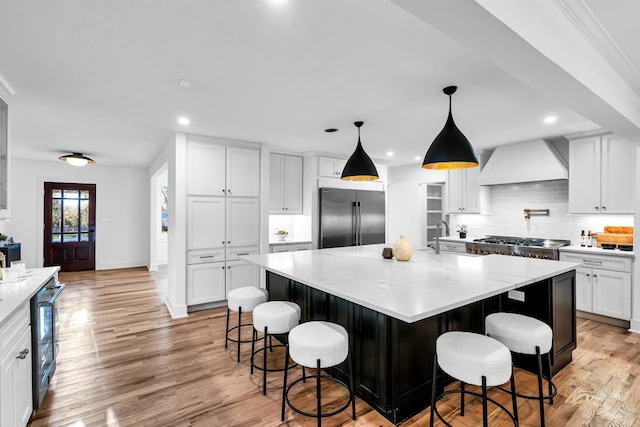 kitchen featuring a large island, custom exhaust hood, stainless steel appliances, and light hardwood / wood-style floors