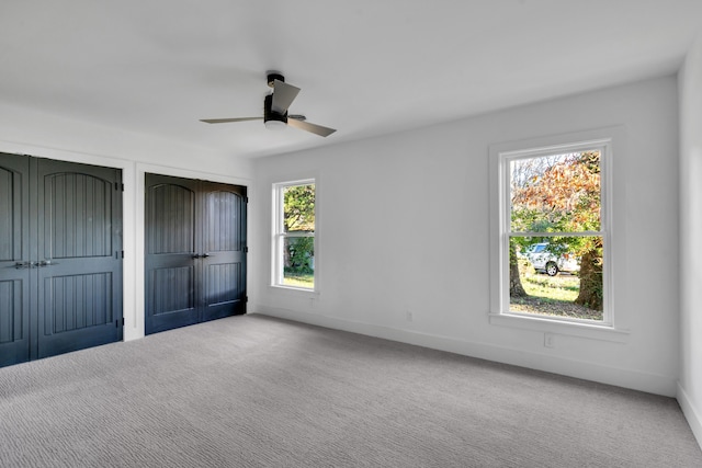 unfurnished bedroom with ceiling fan, carpet, and two closets