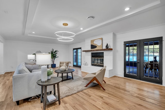 living room featuring plenty of natural light, light wood-type flooring, a fireplace, and french doors