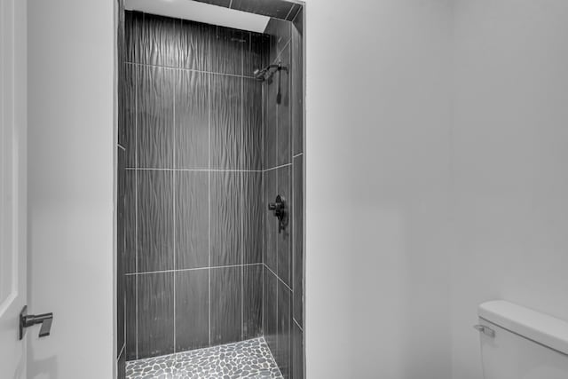 bathroom featuring tiled shower and toilet