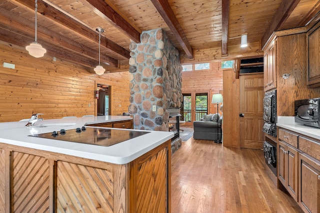 kitchen featuring beamed ceiling, black appliances, wood ceiling, light hardwood / wood-style floors, and decorative light fixtures