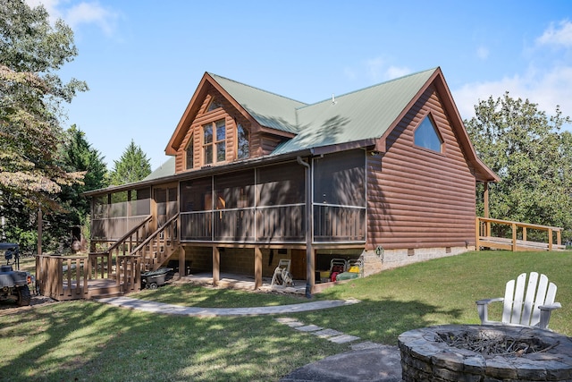 rear view of house with an outdoor fire pit, a yard, a sunroom, and a wooden deck