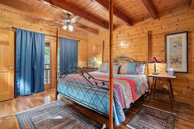 bedroom featuring wood walls, ceiling fan, wooden ceiling, hardwood / wood-style floors, and beam ceiling