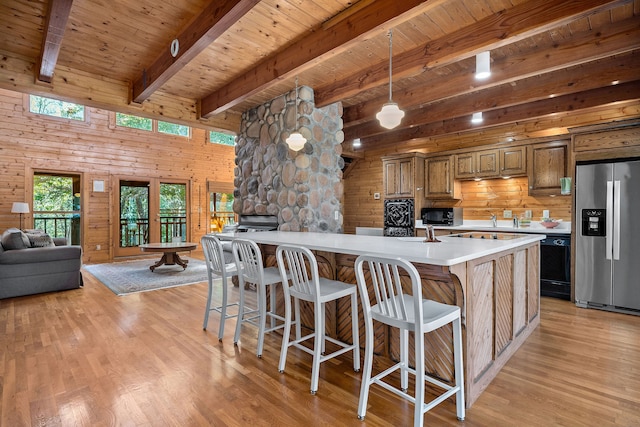 kitchen with light hardwood / wood-style floors, beamed ceiling, black appliances, and wooden walls