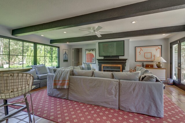 living room featuring ceiling fan, light tile patterned floors, beam ceiling, and a healthy amount of sunlight