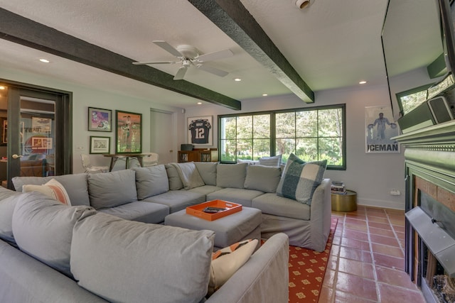 tiled living room featuring a textured ceiling, a tile fireplace, beam ceiling, and ceiling fan