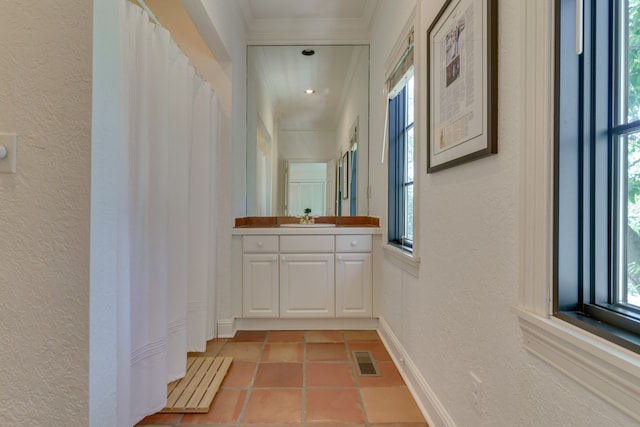 hall with crown molding, sink, and light tile patterned floors