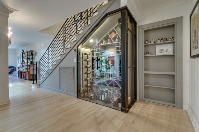 wine cellar featuring crown molding, hardwood / wood-style flooring, and built in features