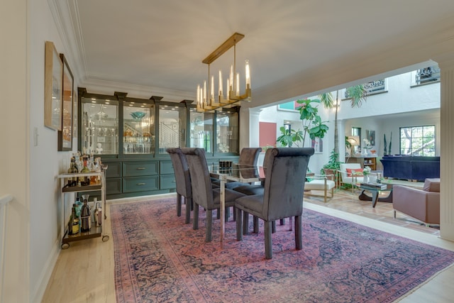 dining space featuring crown molding, light hardwood / wood-style floors, and a notable chandelier