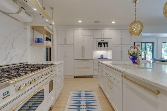 kitchen with built in appliances, sink, range hood, tasteful backsplash, and hanging light fixtures