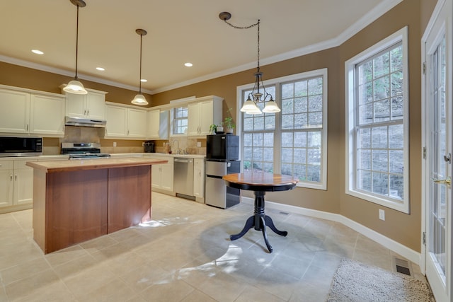 kitchen featuring decorative backsplash, ornamental molding, pendant lighting, white cabinetry, and appliances with stainless steel finishes