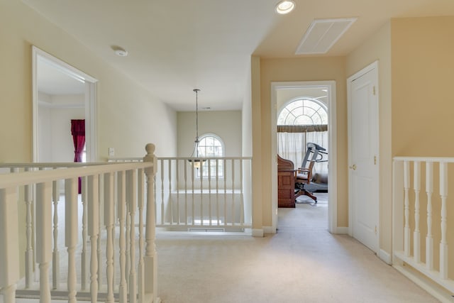 corridor featuring a notable chandelier and light carpet