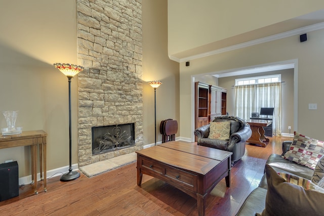 living room with crown molding, a fireplace, and wood-type flooring