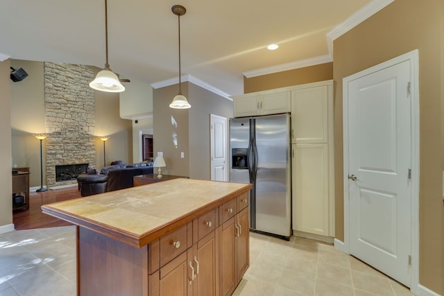 kitchen with stainless steel fridge, crown molding, decorative light fixtures, a fireplace, and a center island