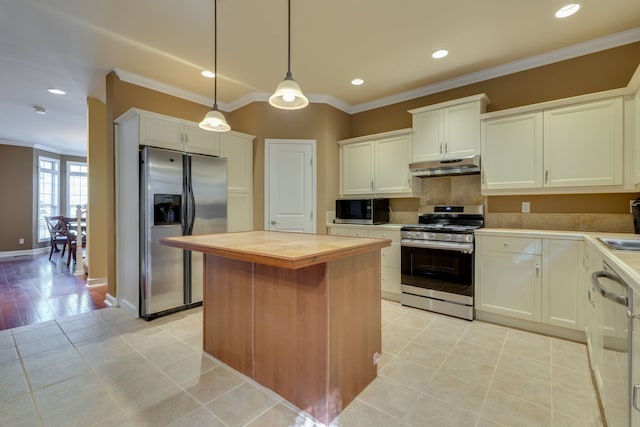 kitchen featuring a center island, stainless steel appliances, crown molding, white cabinetry, and decorative light fixtures