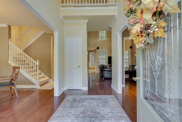 entrance foyer featuring a towering ceiling, dark hardwood / wood-style floors, and crown molding