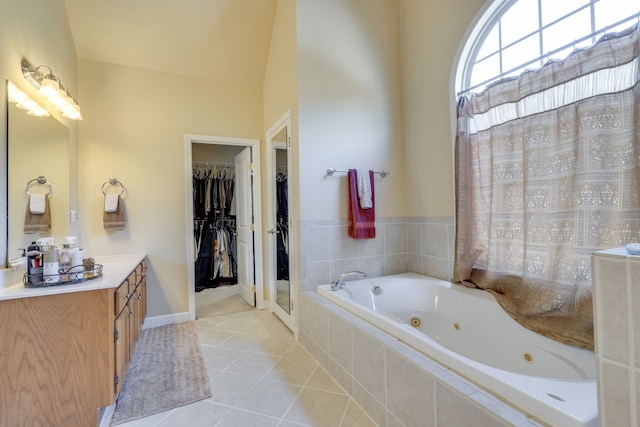 bathroom featuring vaulted ceiling, vanity, tiled bath, and tile patterned flooring