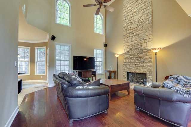 living room featuring hardwood / wood-style flooring, a fireplace, and a towering ceiling