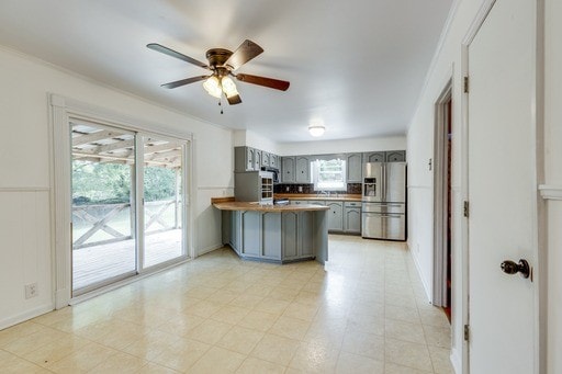 kitchen with stainless steel fridge, kitchen peninsula, gray cabinets, wooden counters, and ceiling fan