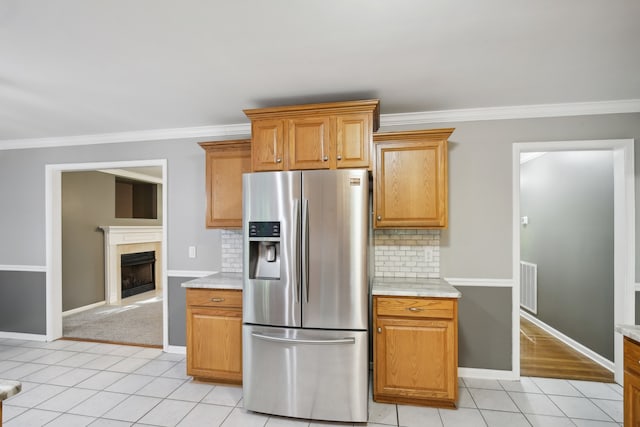 kitchen featuring tasteful backsplash, crown molding, light tile patterned floors, and stainless steel fridge