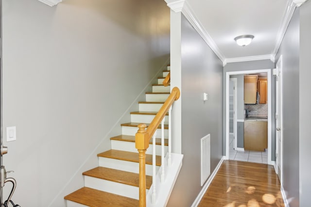 stairs with ornamental molding and hardwood / wood-style floors