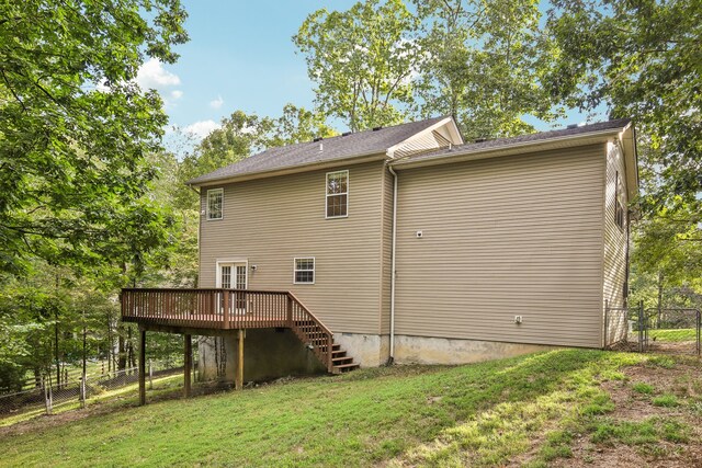 rear view of property featuring a wooden deck and a lawn