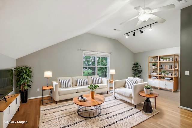 living room featuring ceiling fan, lofted ceiling, rail lighting, and light hardwood / wood-style flooring