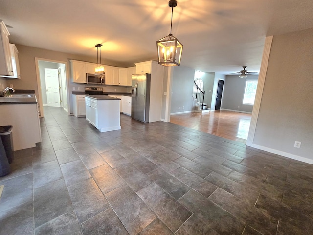 kitchen with white cabinets, ceiling fan with notable chandelier, stainless steel appliances, decorative light fixtures, and sink