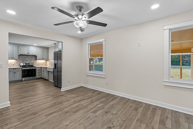 kitchen with gray cabinetry, ceiling fan, appliances with stainless steel finishes, and light hardwood / wood-style flooring