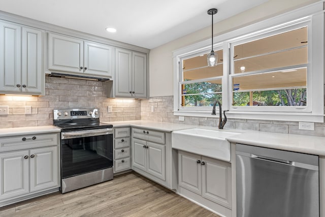 kitchen featuring tasteful backsplash, appliances with stainless steel finishes, sink, gray cabinets, and light hardwood / wood-style flooring