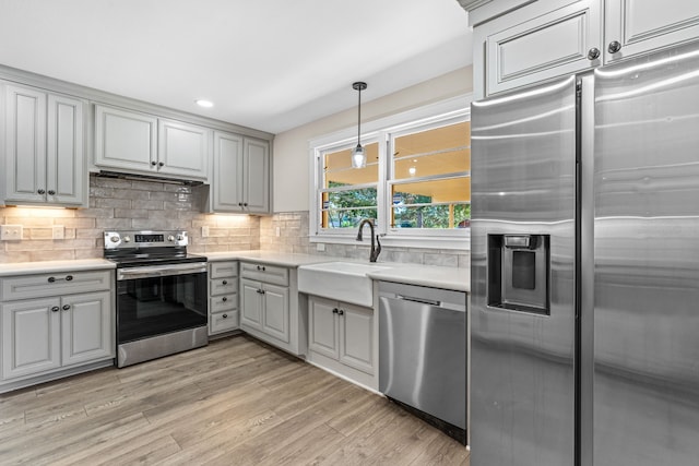 kitchen featuring stainless steel appliances, sink, light wood-type flooring, and gray cabinets