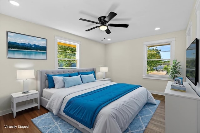 bedroom featuring ceiling fan, multiple windows, and dark hardwood / wood-style floors