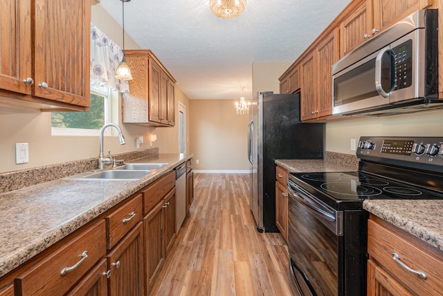 kitchen featuring hanging light fixtures, sink, an inviting chandelier, appliances with stainless steel finishes, and light hardwood / wood-style floors