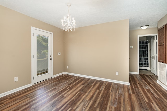 unfurnished room with dark wood-type flooring, a notable chandelier, and a textured ceiling