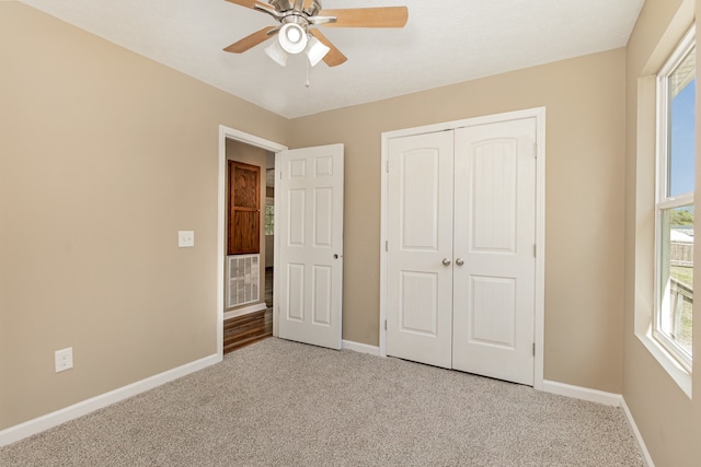 unfurnished bedroom featuring light carpet, a closet, and ceiling fan