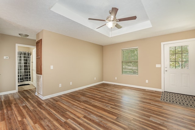 interior space featuring a textured ceiling, ceiling fan, a raised ceiling, and dark hardwood / wood-style flooring