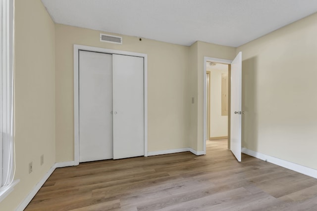 unfurnished bedroom with a closet, a textured ceiling, and light wood-type flooring