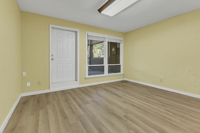 unfurnished room featuring a textured ceiling and light wood-type flooring