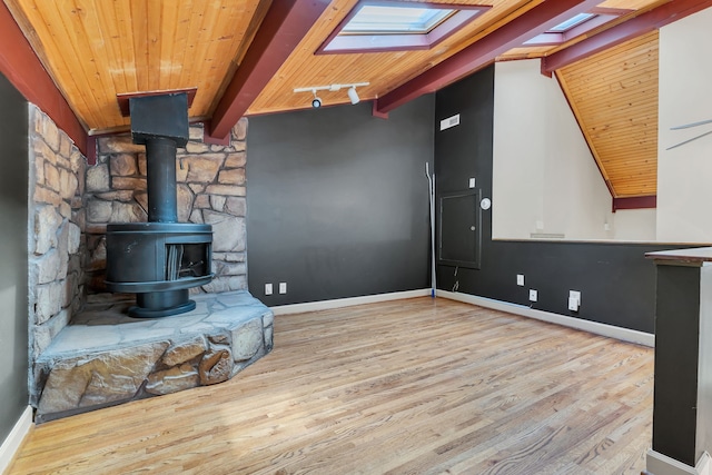 unfurnished living room featuring lofted ceiling with skylight, light hardwood / wood-style flooring, a wood stove, and wooden ceiling