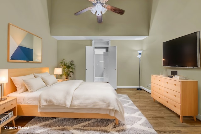 bedroom with ceiling fan, hardwood / wood-style flooring, and a towering ceiling